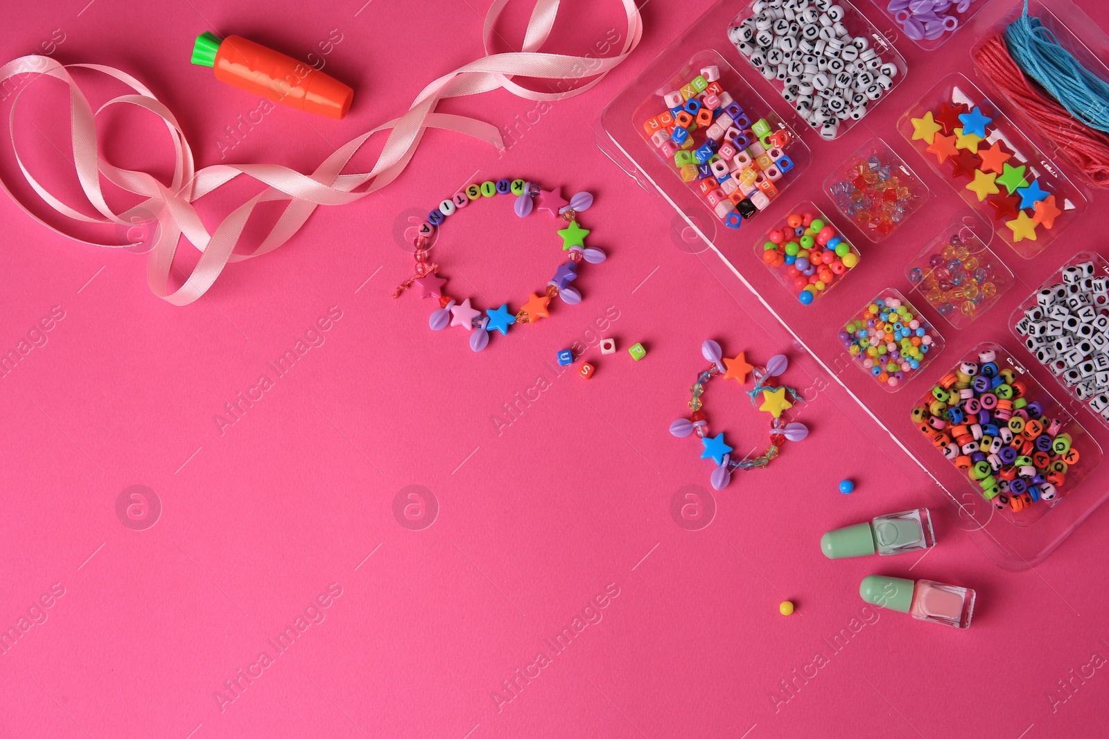 Photo of Handmade jewelry kit for kids. Colorful beads, ribbon and bracelets on bright pink background, flat lay. Space for text