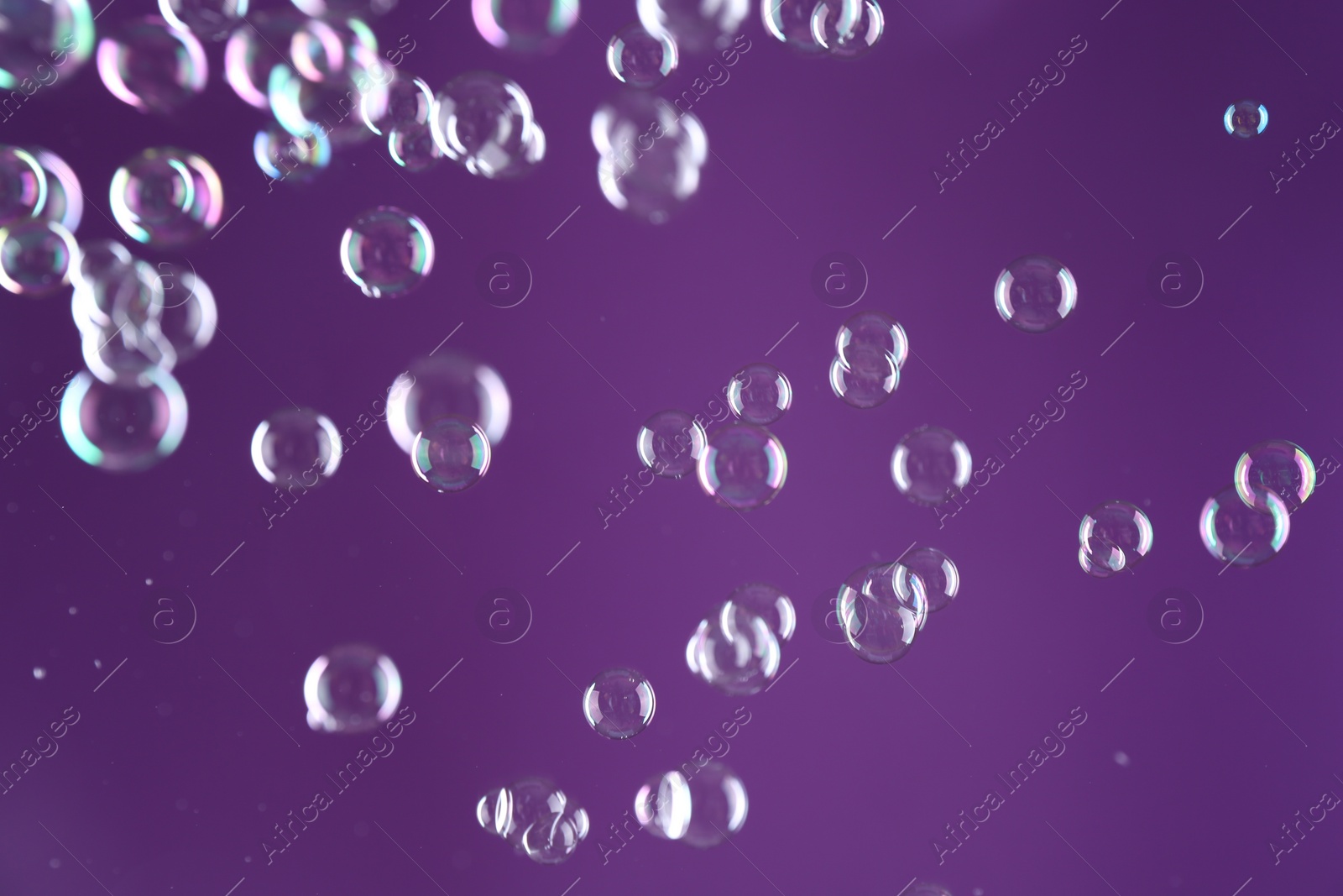 Photo of Beautiful transparent soap bubbles on purple background