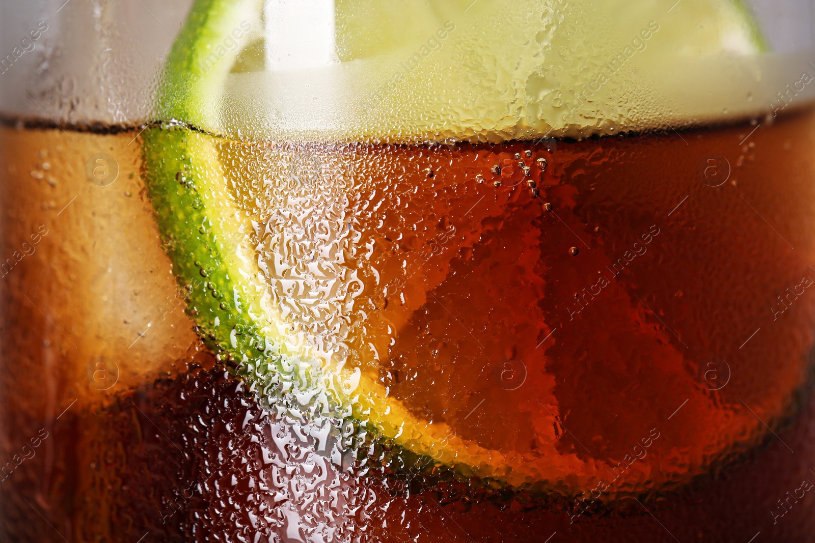 Photo of Glass of refreshing drink with sliced lime and ice cubes as background, closeup