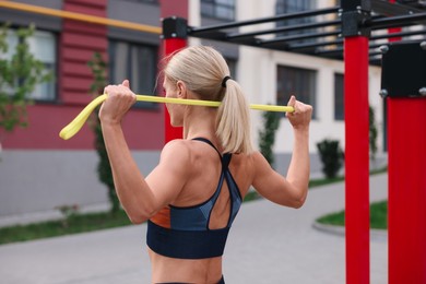 Photo of Athletic woman doing exercise with fitness elastic band at outdoor gym