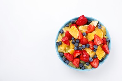 Yummy fruit salad in bowl on white background, top view. Space for text