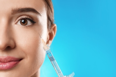 Photo of Beautiful woman getting facial injection on light blue background, closeup. Cosmetic surgery