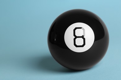 Photo of One magic eight ball on light blue background, space for text