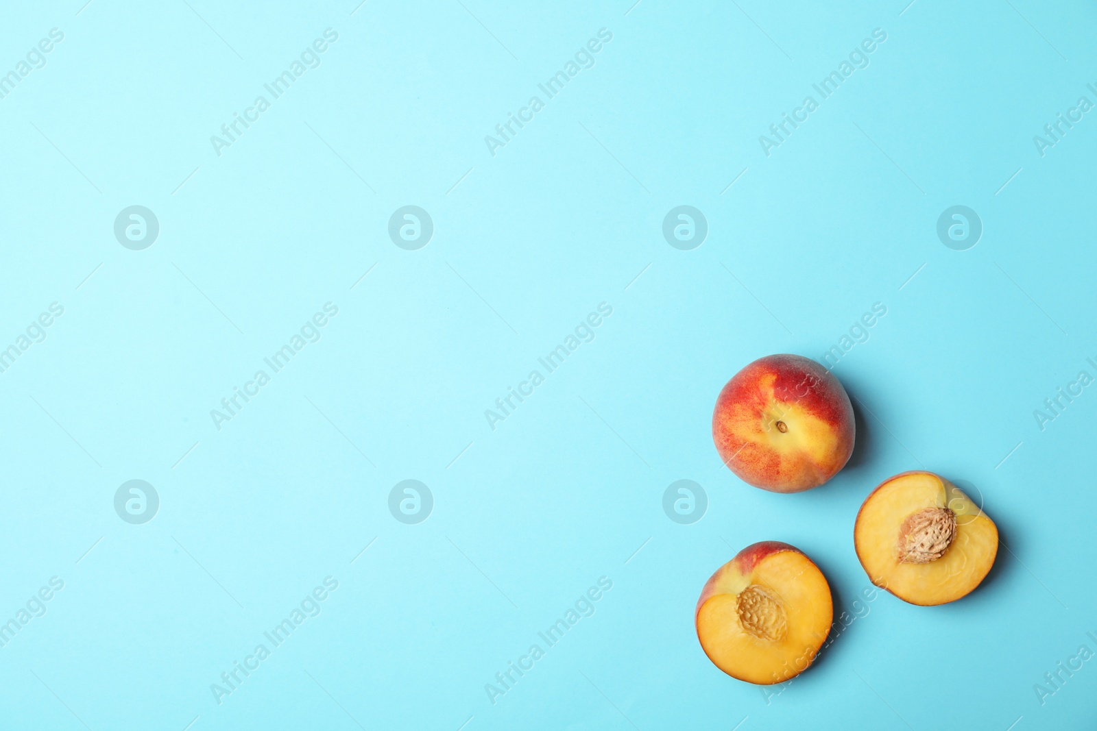 Photo of Sweet juicy peaches on light blue background, top view. Space for text