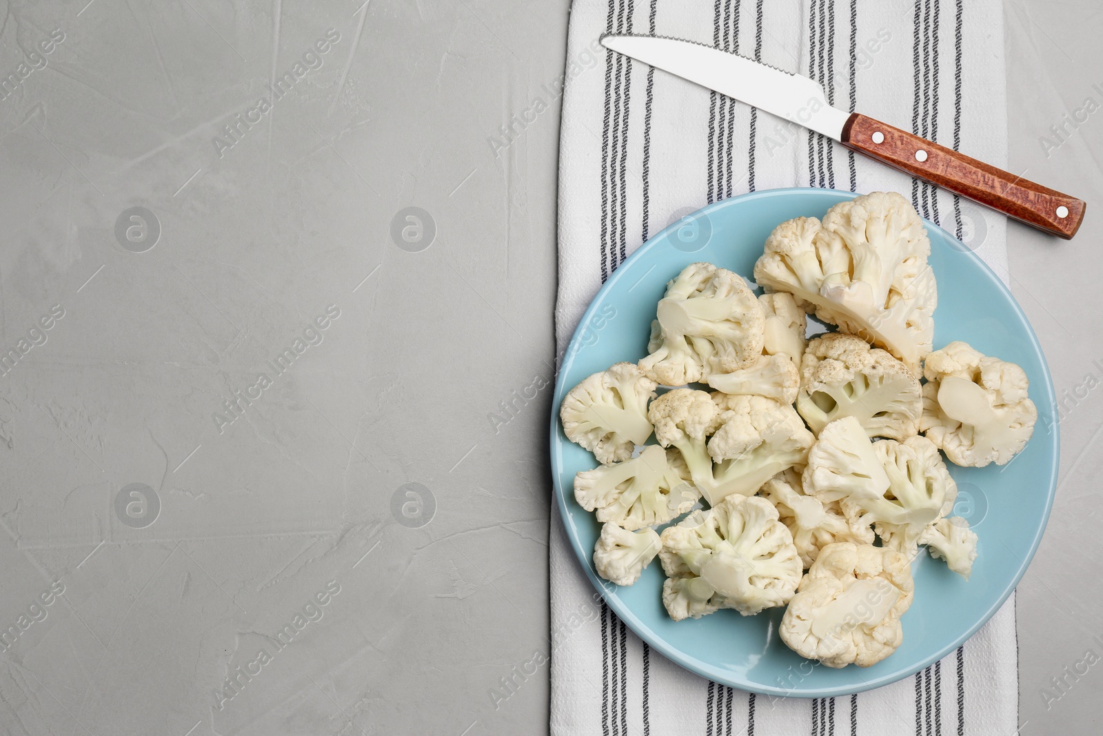 Photo of Plate with cut fresh raw cauliflower on light grey table, flat lay. Space for text