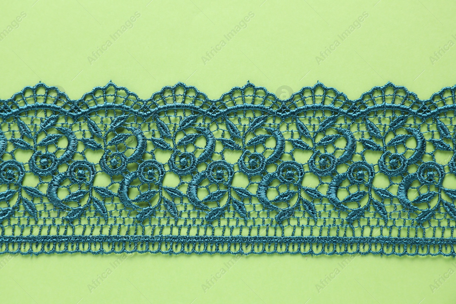 Photo of Beautiful lace on green background, top view