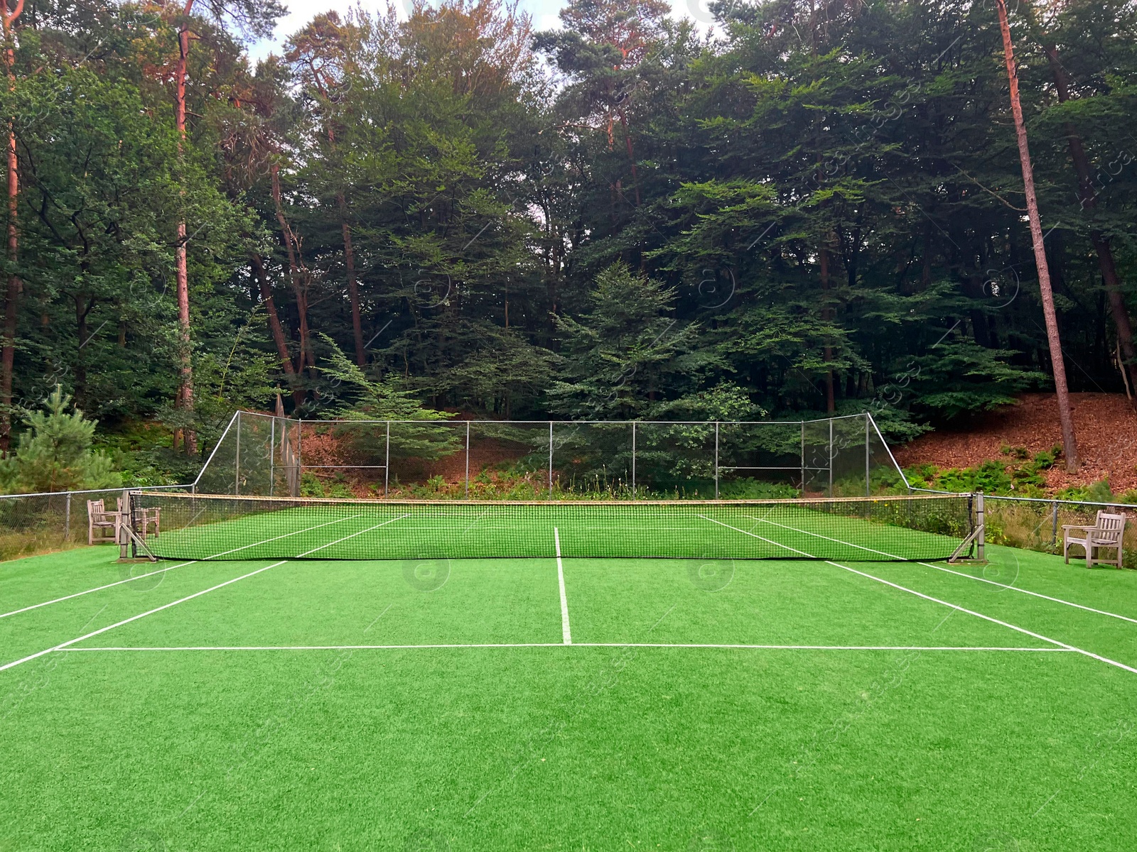 Photo of Tennis court with green grass and net outdoors