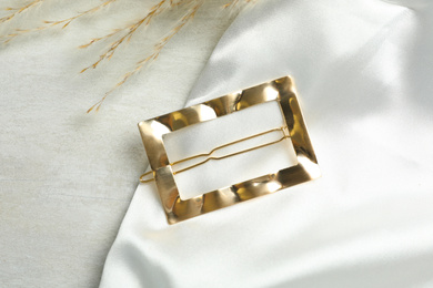Photo of Beautiful gold hair clip on white table, top view
