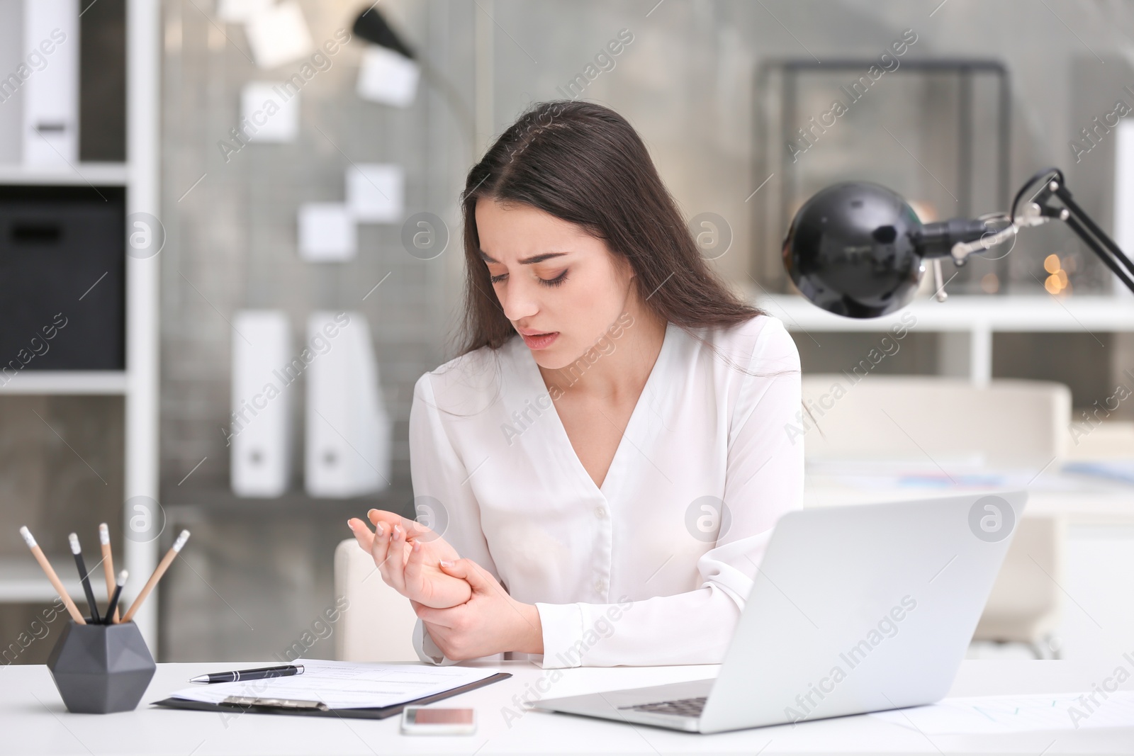 Photo of Young woman suffering from wrist pain in office