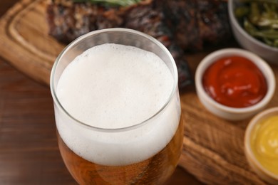 Glass of tasty beer on wooden table, closeup