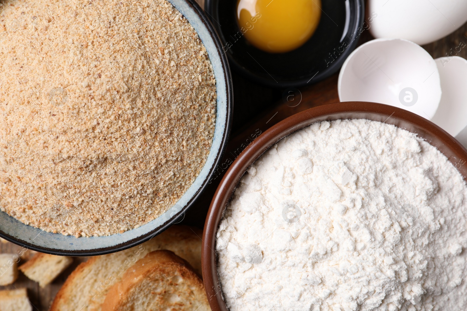 Photo of Fresh breadcrumbs, flour and eggs on table, top view