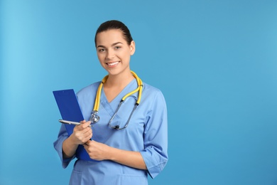 Photo of Portrait of young medical assistant with stethoscope and clipboard on color background. Space for text