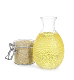 Glass bottle of fresh sesame oil and jar with seeds isolated on white