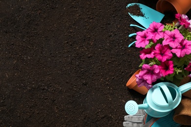 Photo of Flat lay composition with gardening equipment and flowers on soil, space for text