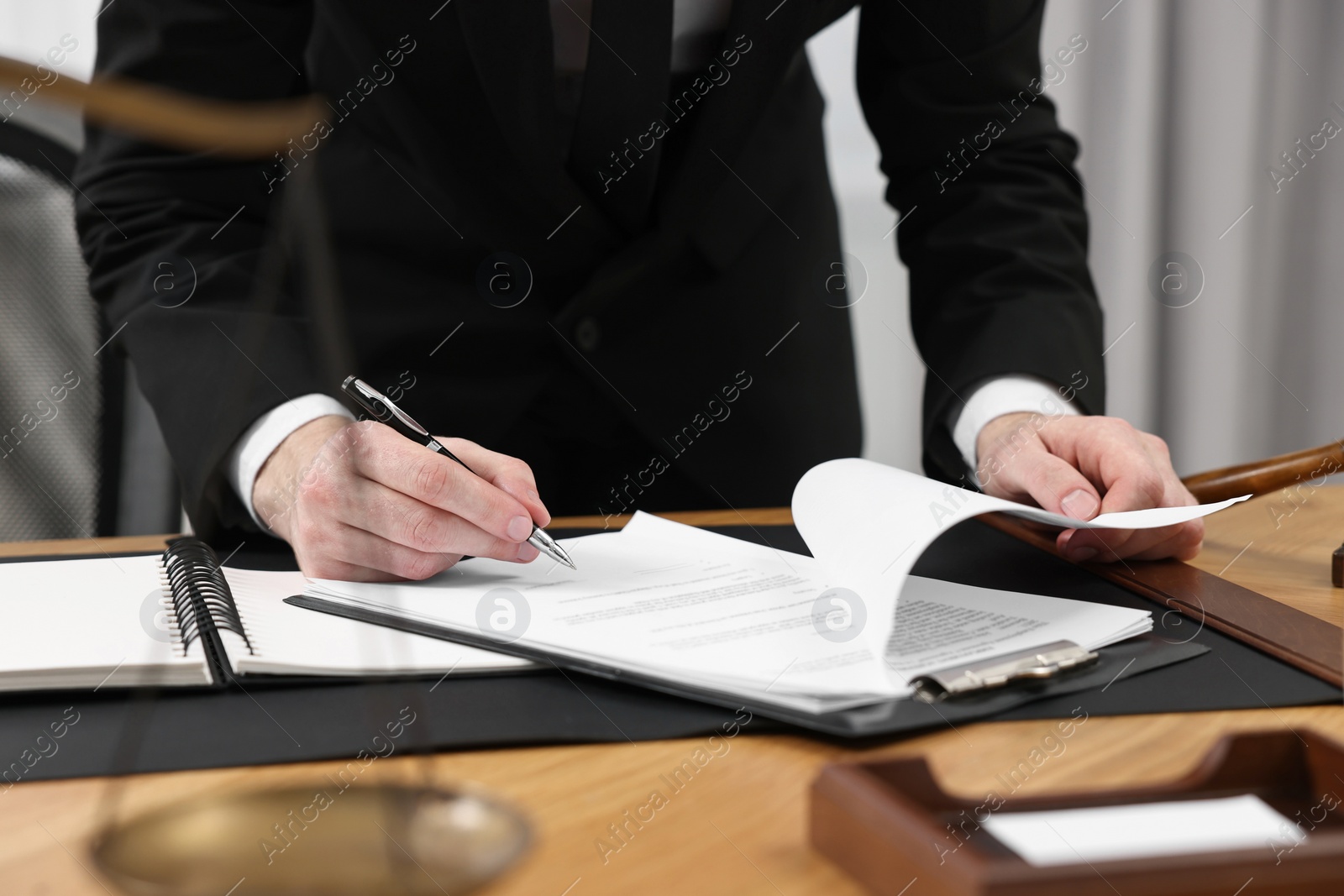 Photo of Lawyer working with documents at wooden table indoors, closeup