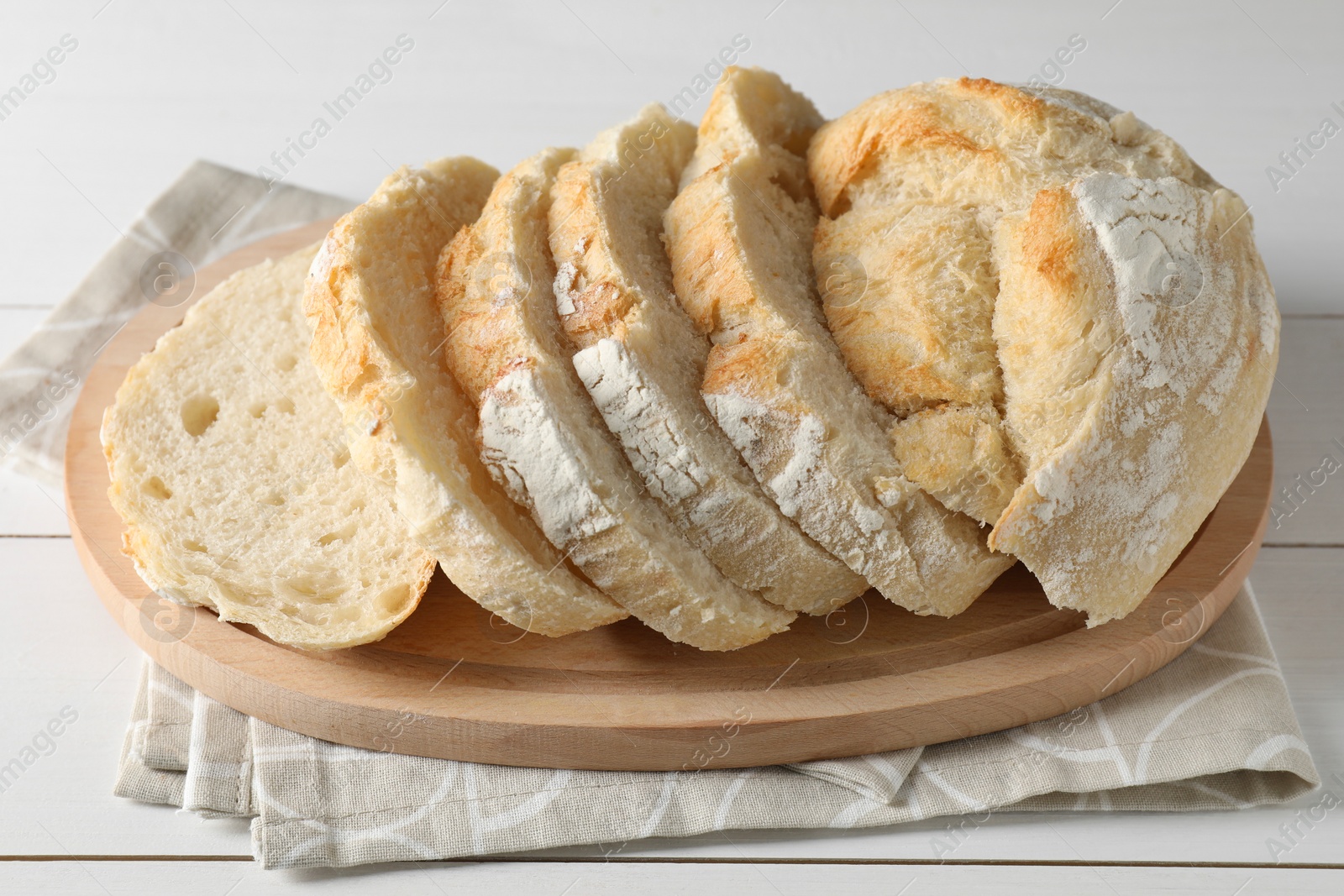 Photo of Freshly baked cut sourdough bread on white wooden table