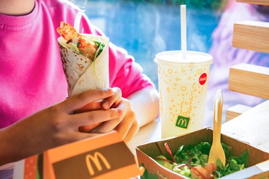 Photo of WARSAW, POLAND - SEPTEMBER 16, 2022: Woman eating roll with chicken in McDonald's cafe, closeup