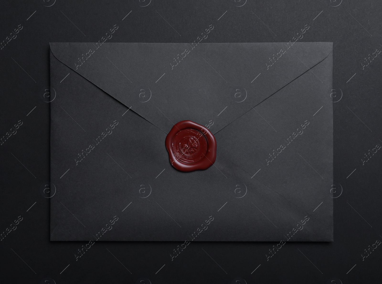 Photo of Envelope with wax seal on black background, top view