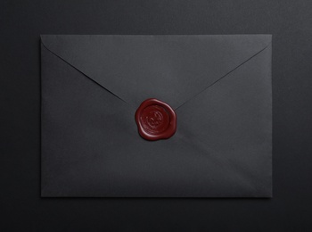 Photo of Envelope with wax seal on black background, top view