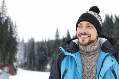 Photo of Happy man in warm clothes outdoors, space for text. Winter vacation