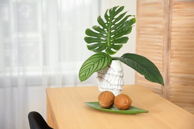 Vase with tropical leaves on table indoors. Interior design element