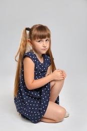 Full length portrait of little girl suffering from knee problems on grey background