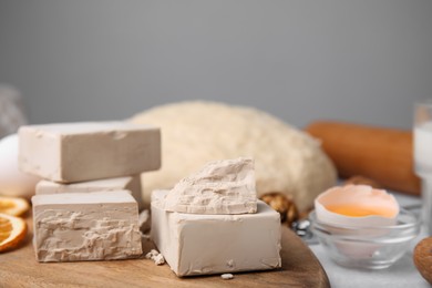 Photo of Blocks of compressed yeast and ingredients on wooden table, closeup