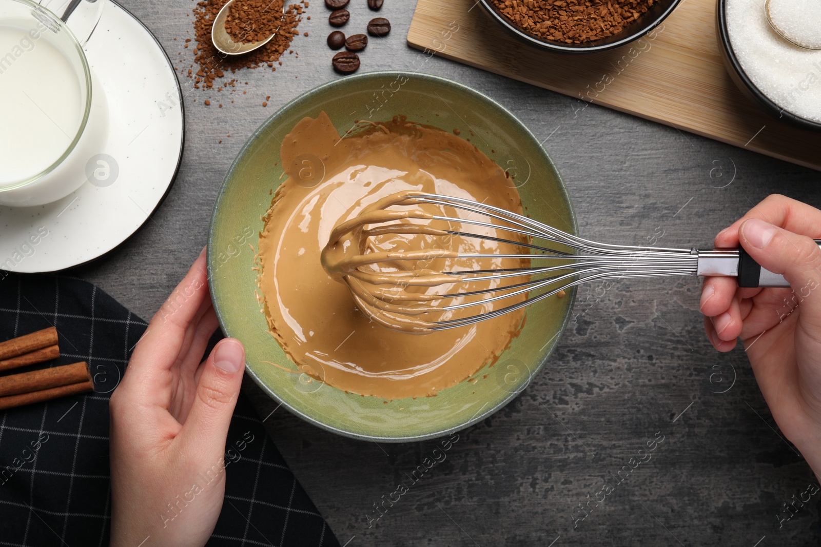 Photo of Woman whipping cream for dalgona coffee at gray table, top view