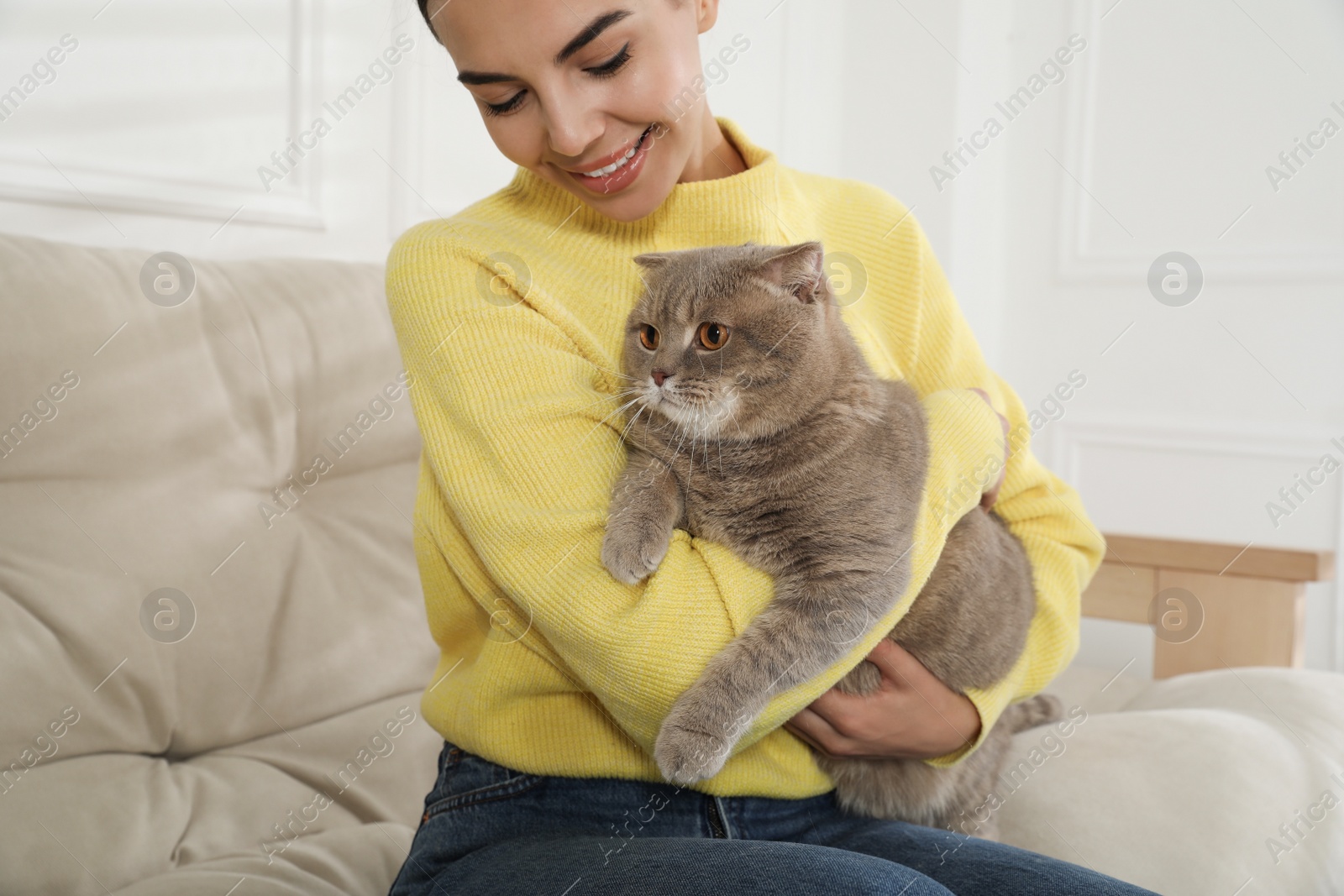 Photo of Woman with her adorable cat on sofa at home