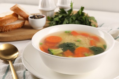 Photo of Delicious vegetable soup with noodles and spoon on table, closeup
