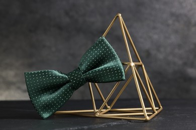 Stylish presentation of green bow tie on black table against gray background