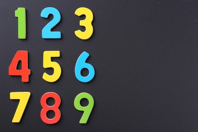 Photo of Colorful numbers on black background, flat lay. Space for text