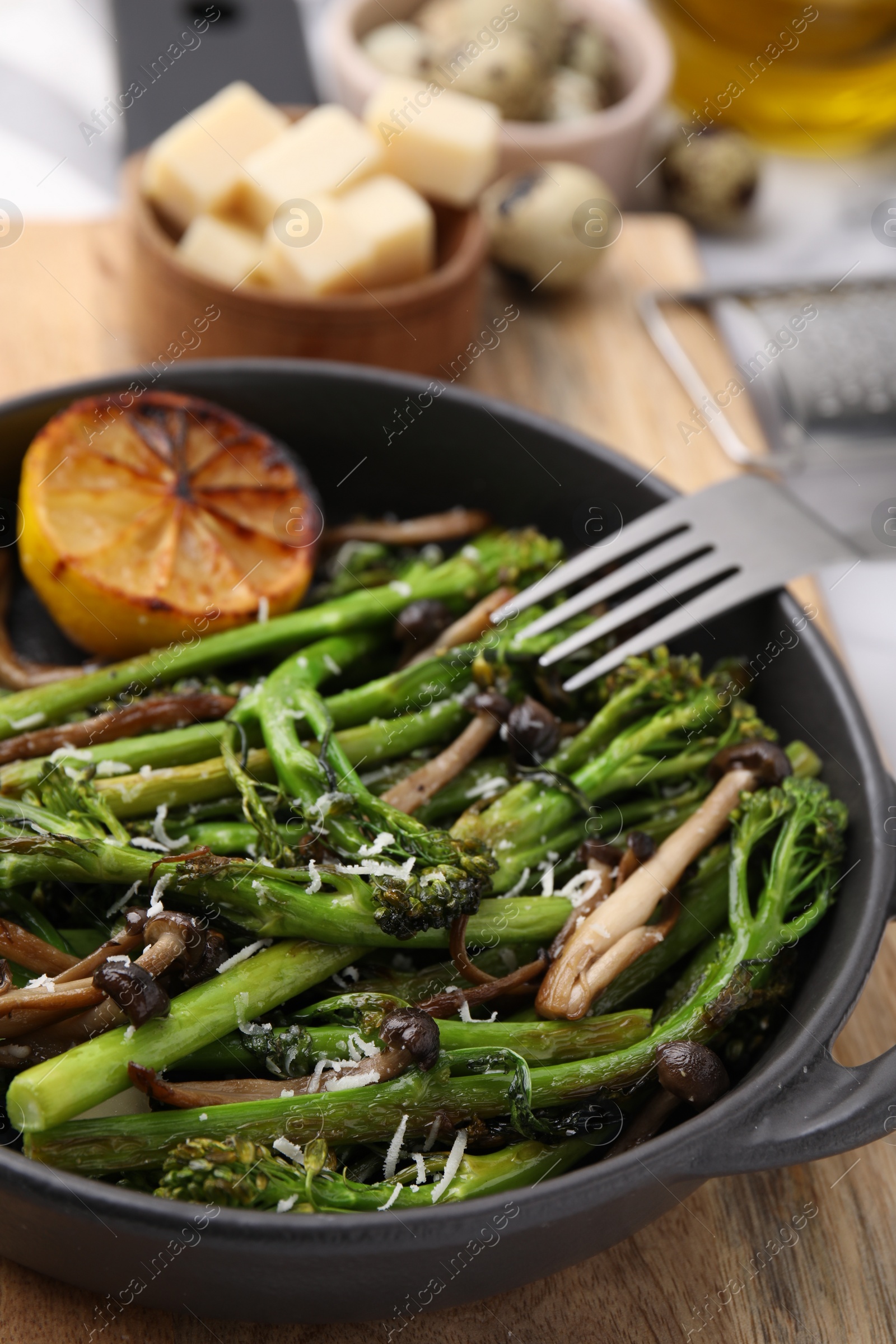 Photo of Tasty cooked broccolini, mushrooms and lemon on board, closeup