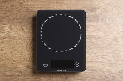 Photo of Modern digital kitchen scale on wooden table, top view
