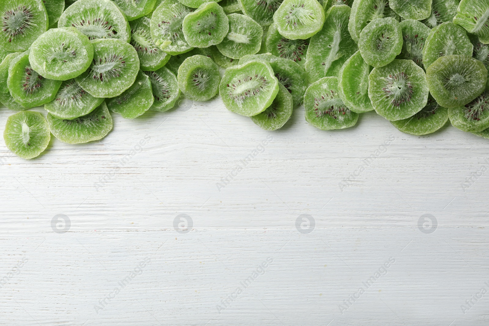 Photo of Slices of kiwi on wooden background, top view with space for text. Dried fruit as healthy food