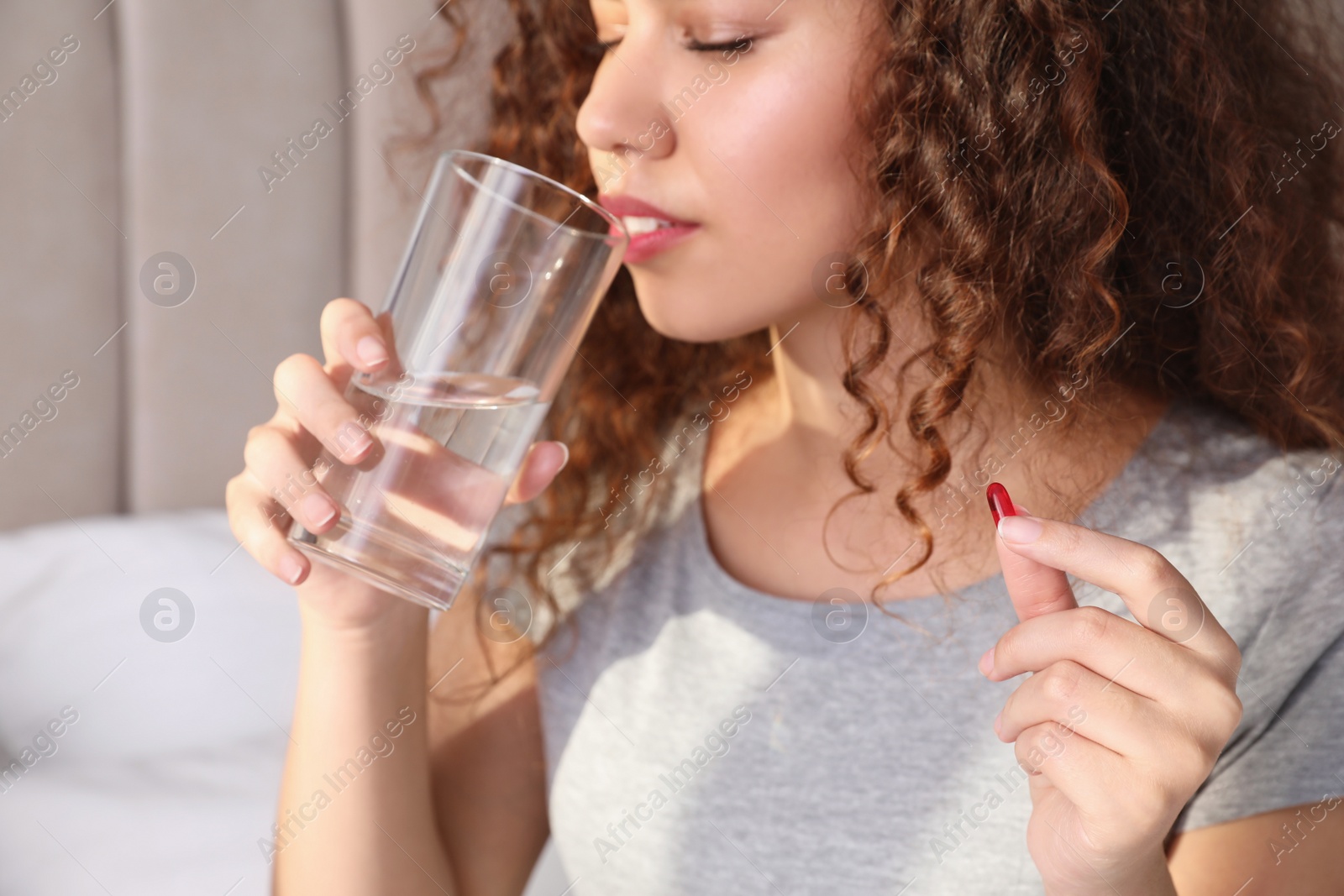 Photo of African-American woman with glass of water and vitamin pill at home, closeup