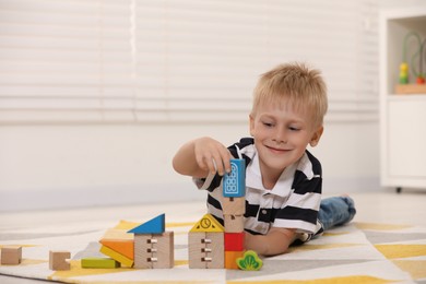 Photo of Cute little boy playing with wooden toys indoors, space for text