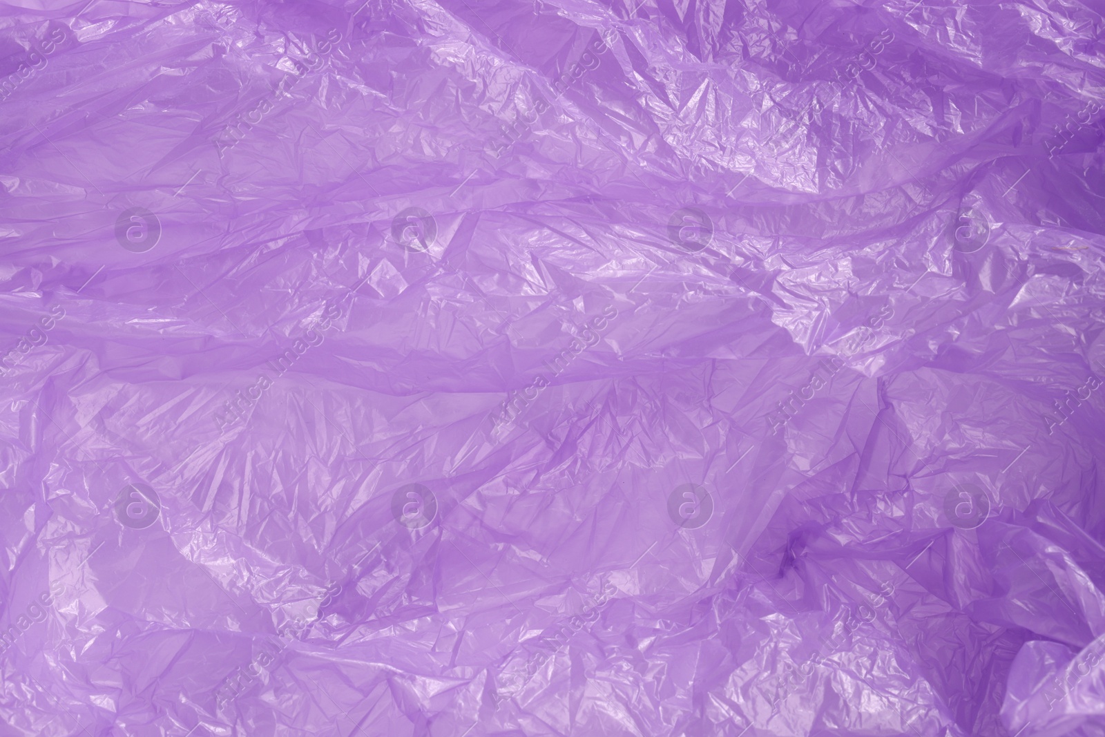 Photo of Crumpled purple plastic bag as background, top view