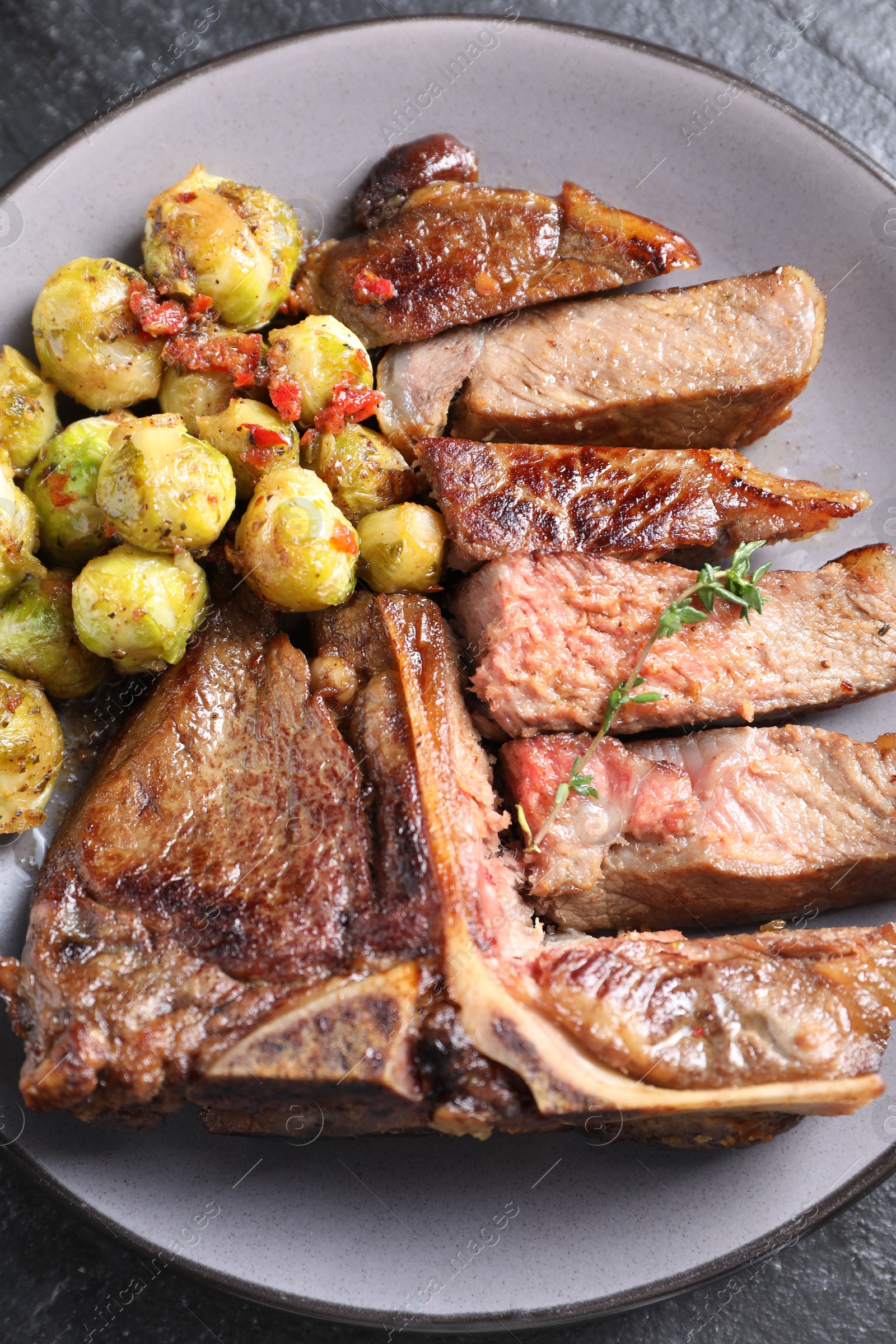 Photo of Delicious fried beef meat, vegetables and thyme on table, top view