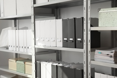 Photo of Folders and boxes with documents on shelves in archive
