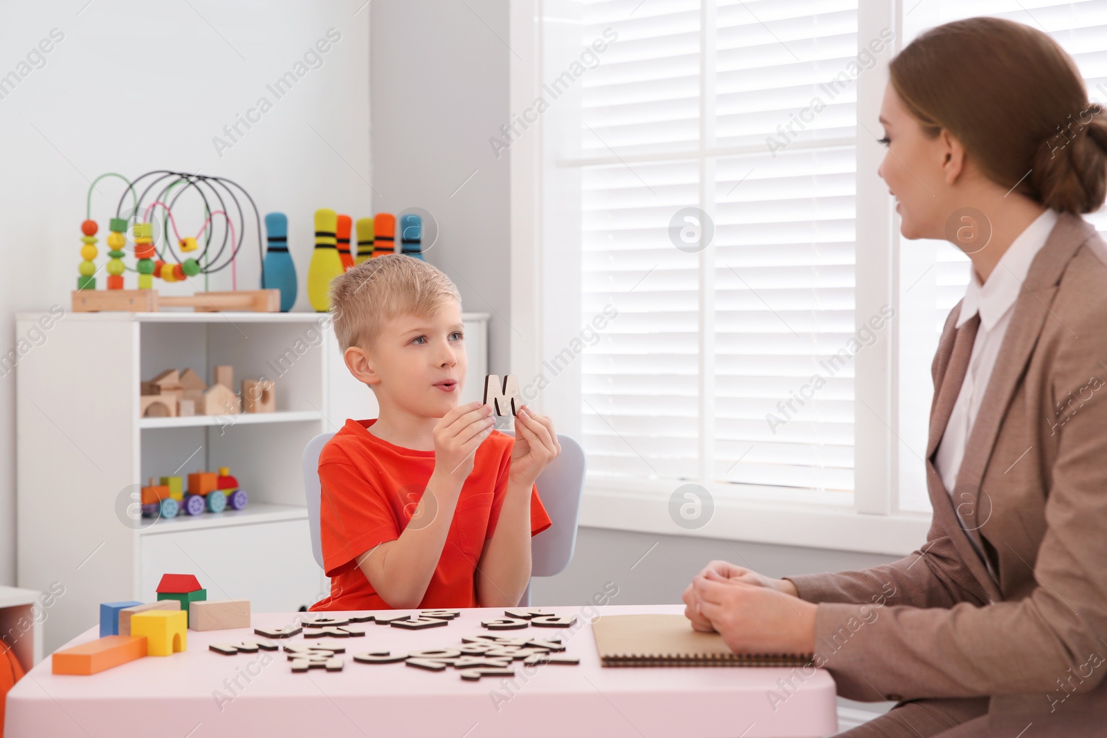 Photo of Speech therapist working with little boy in office