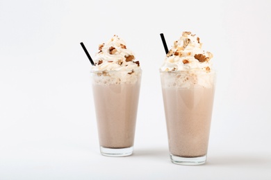 Glasses with delicious milk shakes on white background