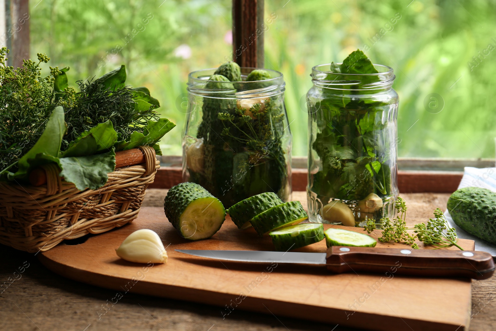 Photo of Glass jars, fresh vegetables and herbs on wooden table indoors. Pickling recipe