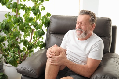 Photo of Senior man suffering from knee pain indoors
