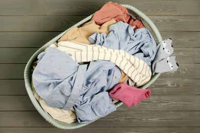Photo of Laundry basket with clothes on dark grey wooden floor, top view