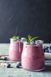 Photo of Tasty blueberry smoothie in jars and  berries on wooden table