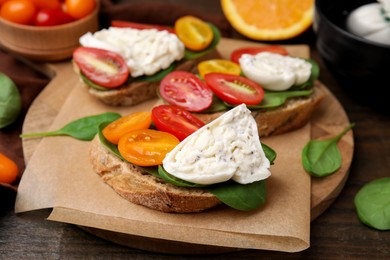 Photo of Delicious sandwiches with burrata cheese and tomatoes on wooden table, closeup