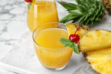 Photo of Glasses with delicious pineapple juice on table