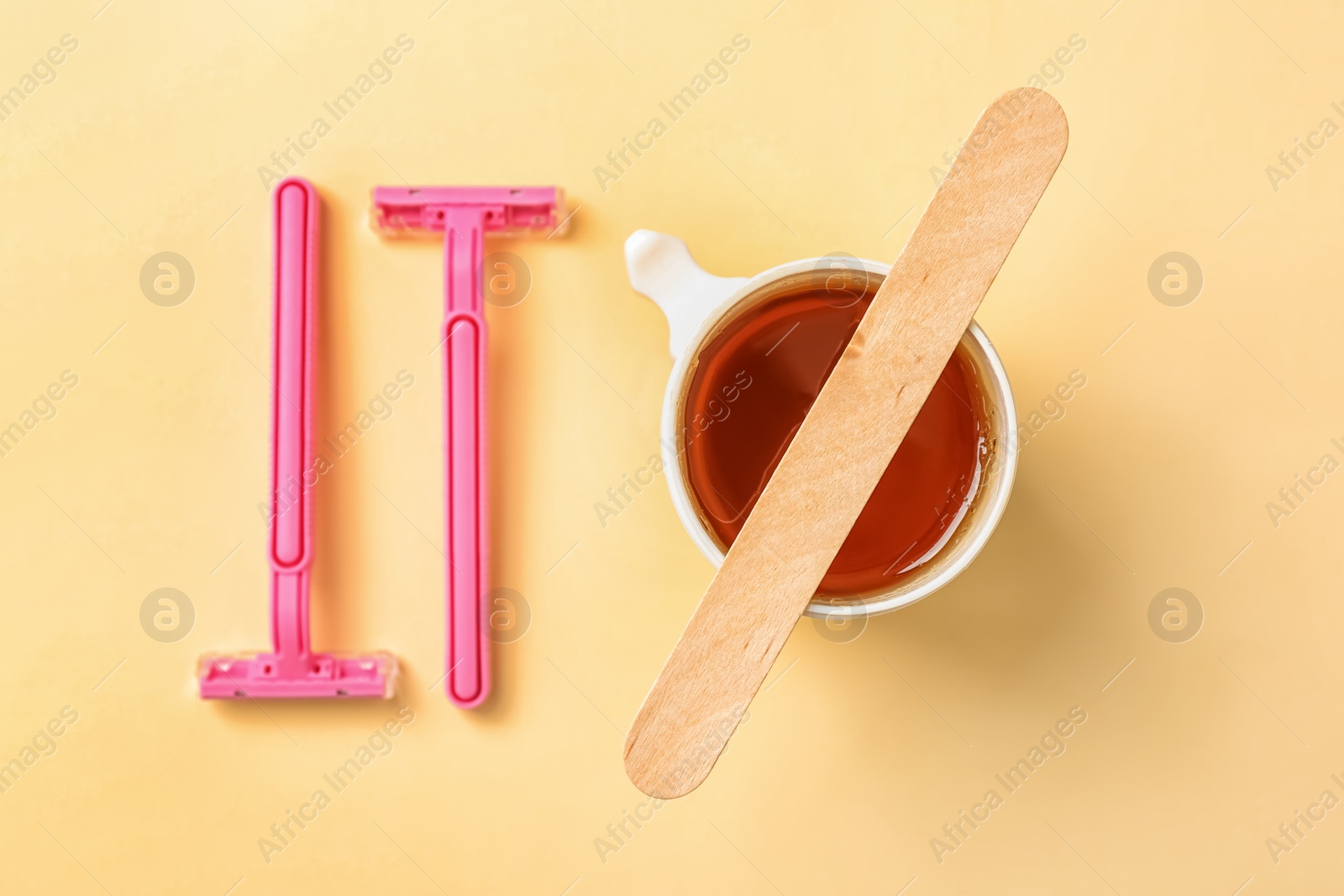 Photo of Sugaring paste and razors on color background, flat lay