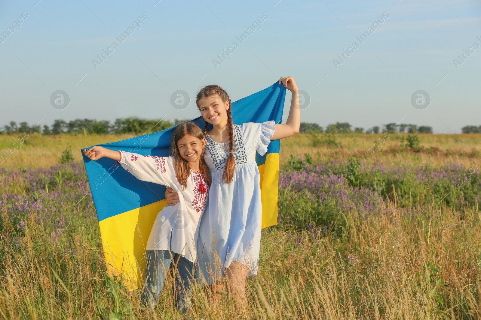 Photo of Happy girls with national flag of Ukraine in field